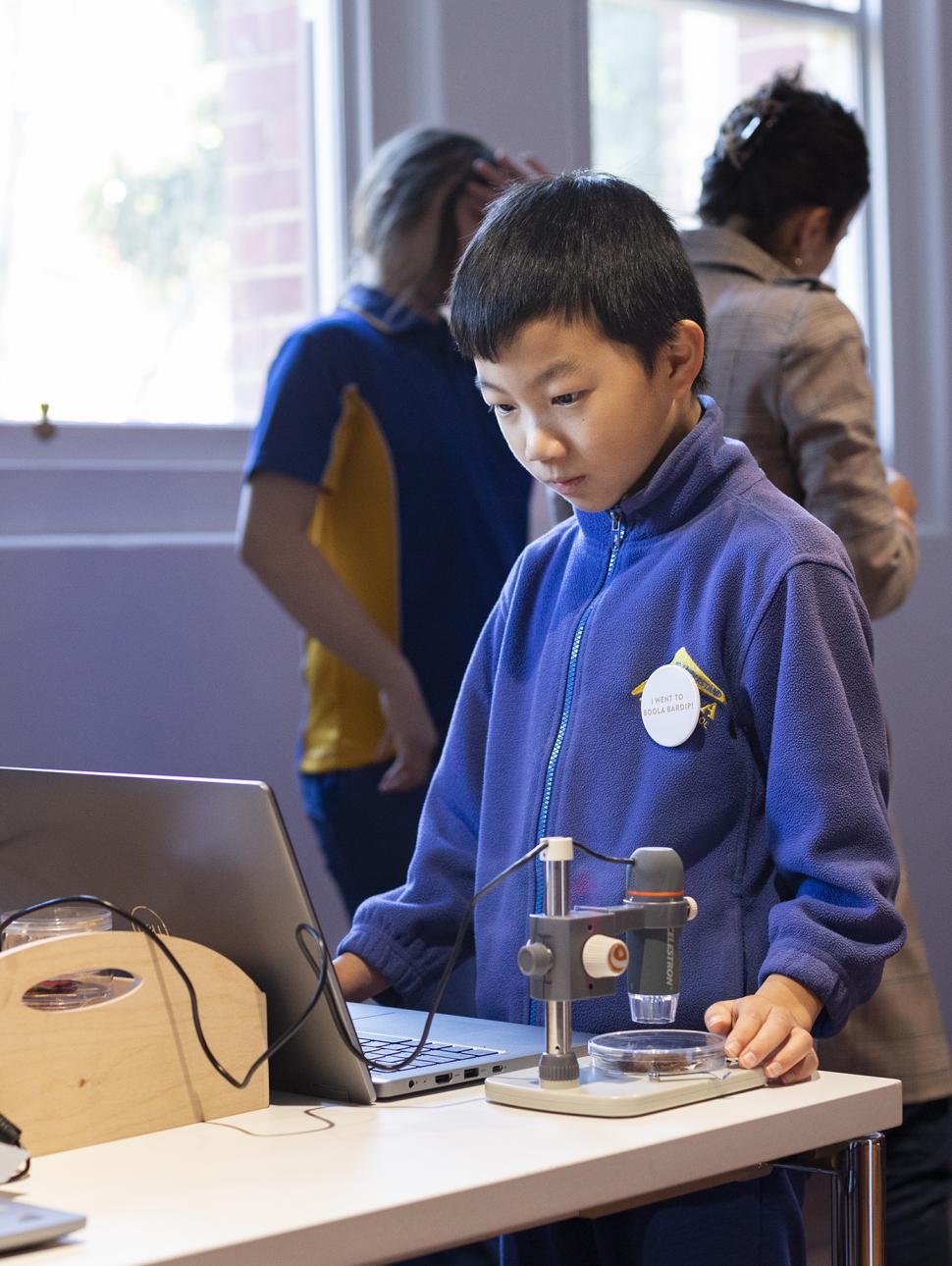 Child looking at a computer screen with a microscope to the side