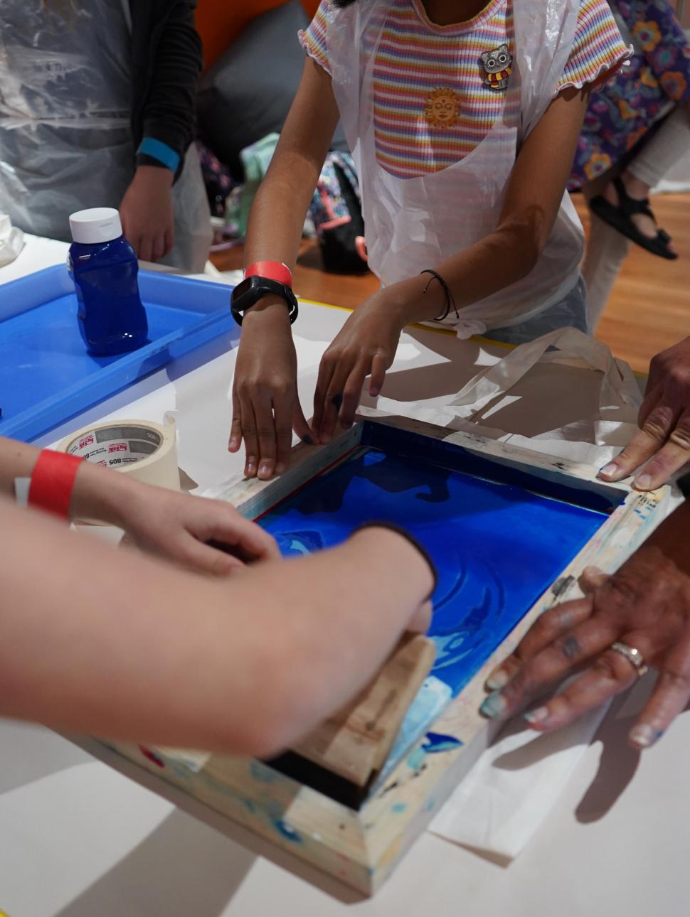 Image shows children using a screen printing frame, paint and squeegee to create an image
