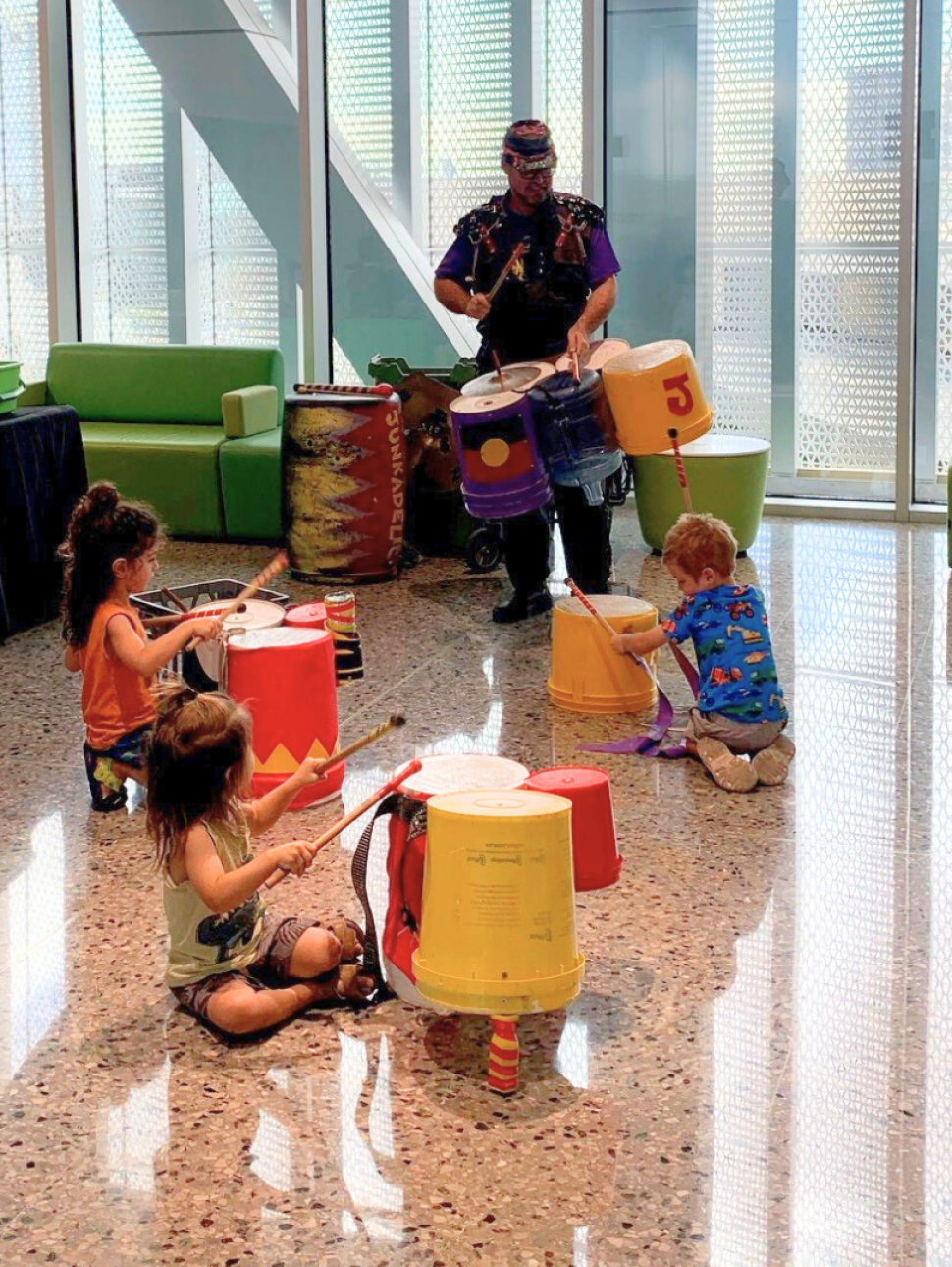 children are playing on instruments made with recycled items and junk