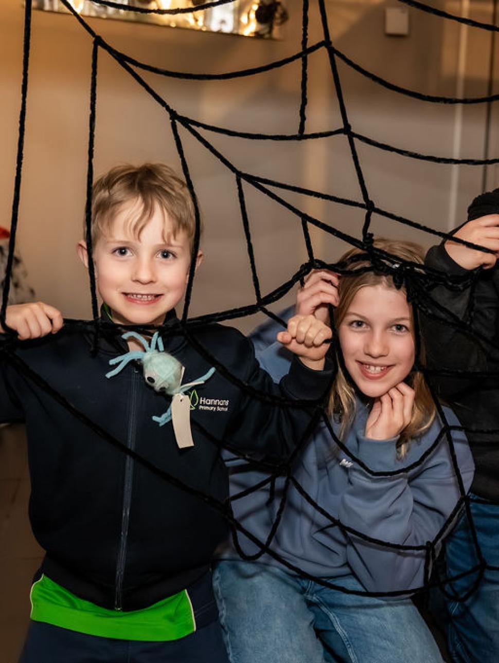 three children look happy and play in between woolen home made spider webs