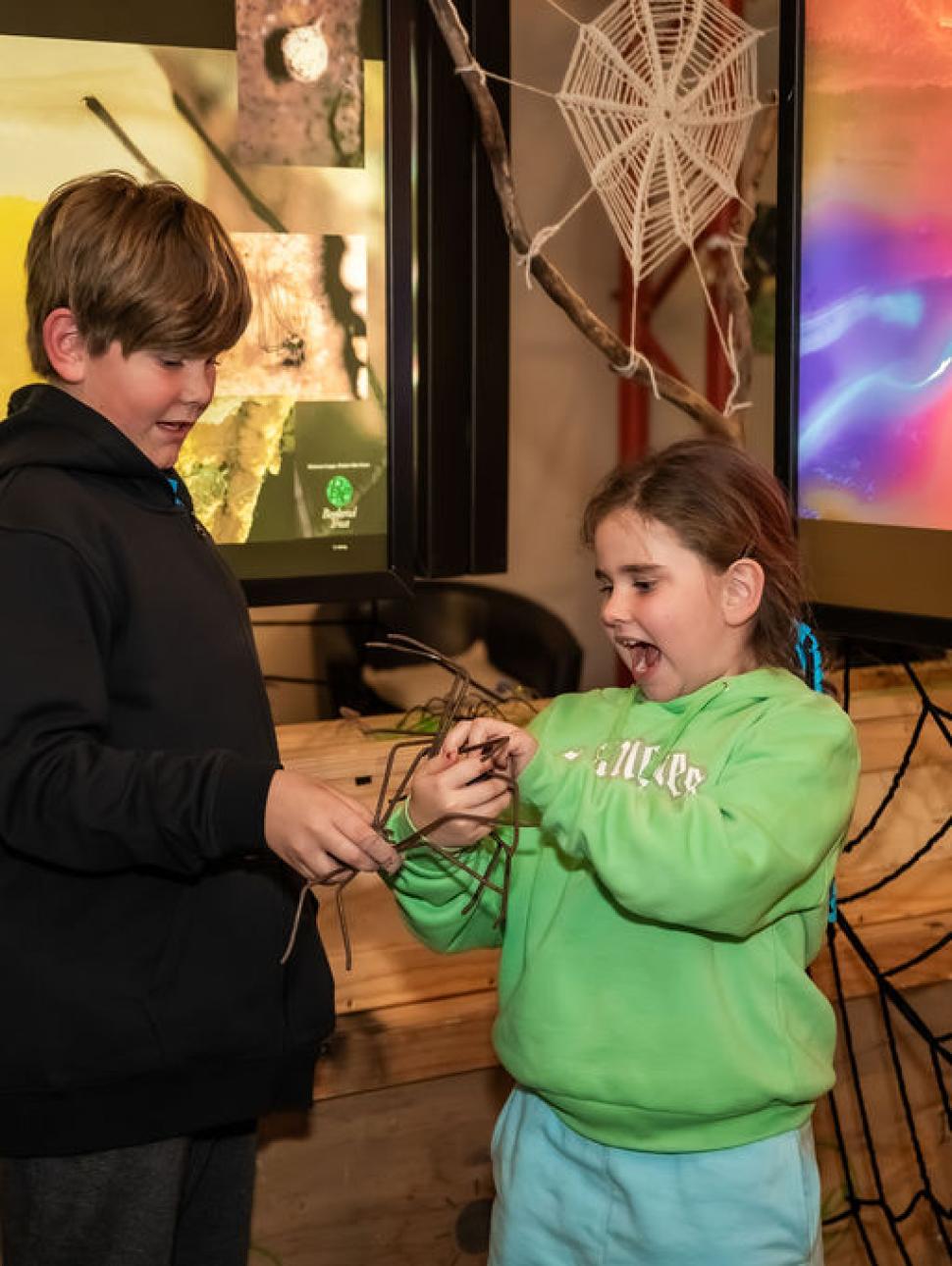 two children are interacting with amedium sized spider model