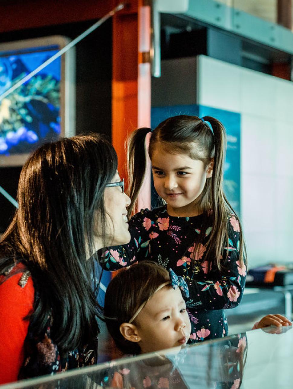 young kids and their parent looking at display cases 