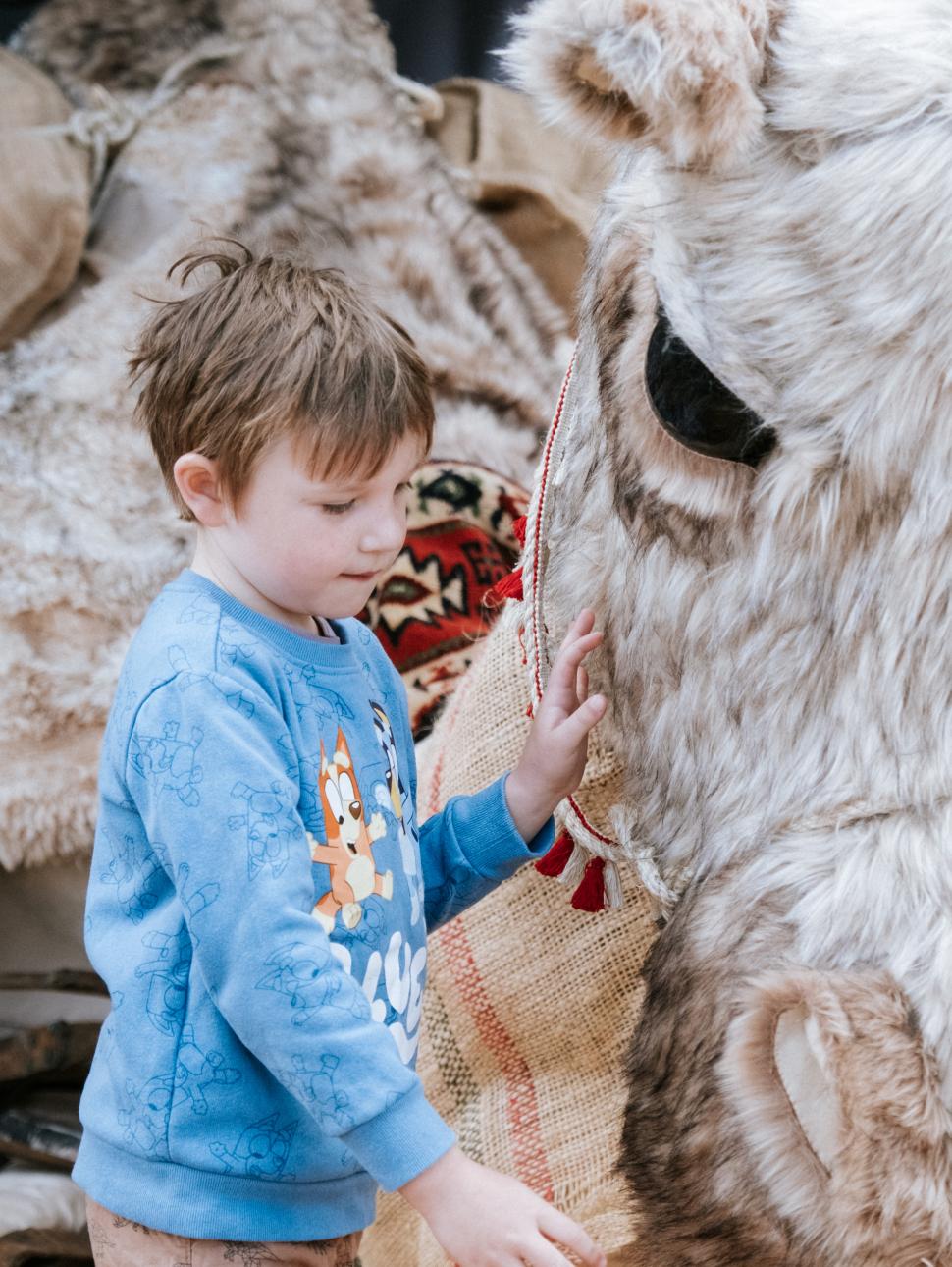 Life-size camel puppet with child standing in front