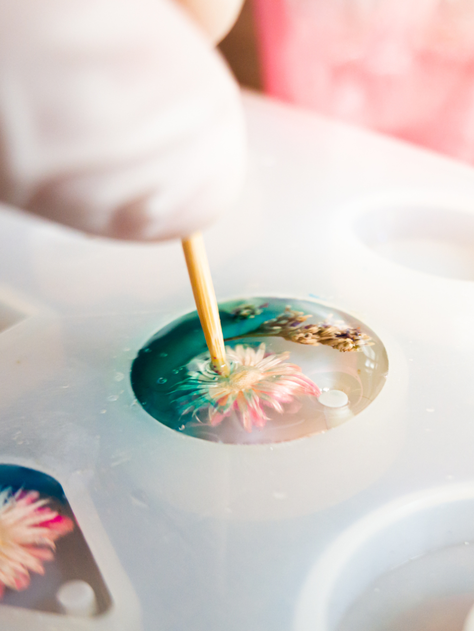 Close-up of a jewelry mold featuring dried flowers and vibrant coloured dye.