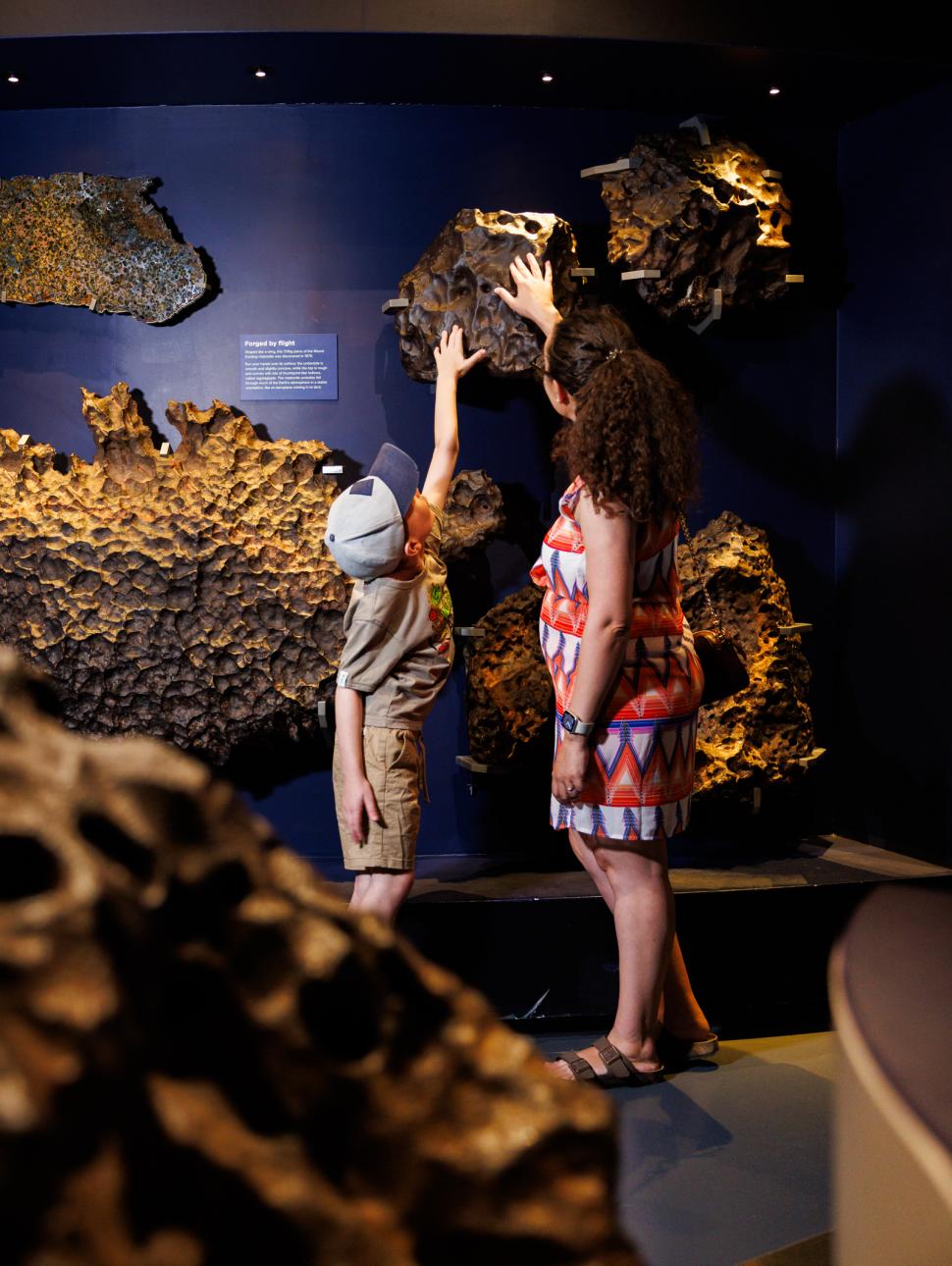 Woman and boy touch meteor inside Museum on the wall