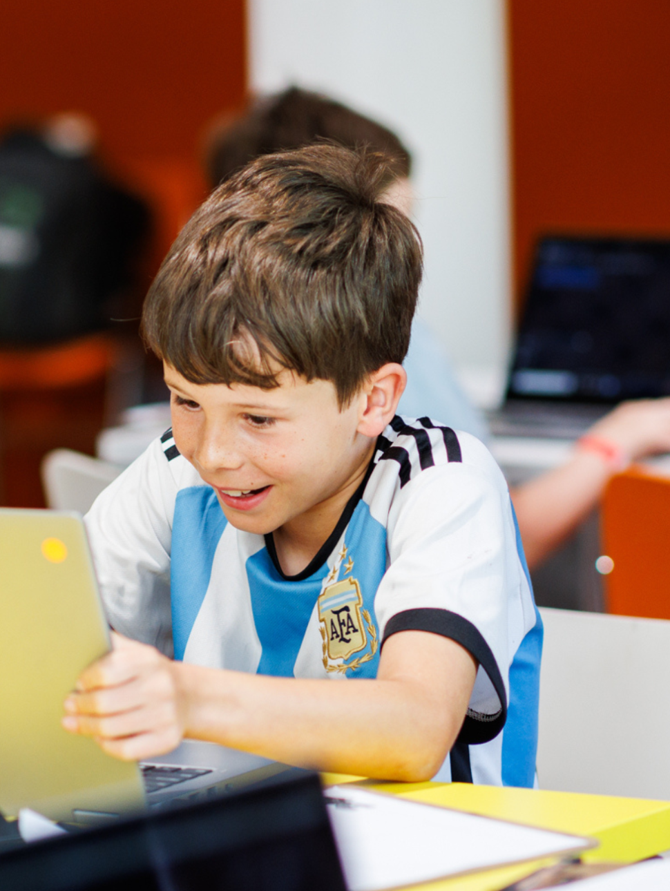 Kids happily participating in a computer program while wearing striped blue and white sports tops