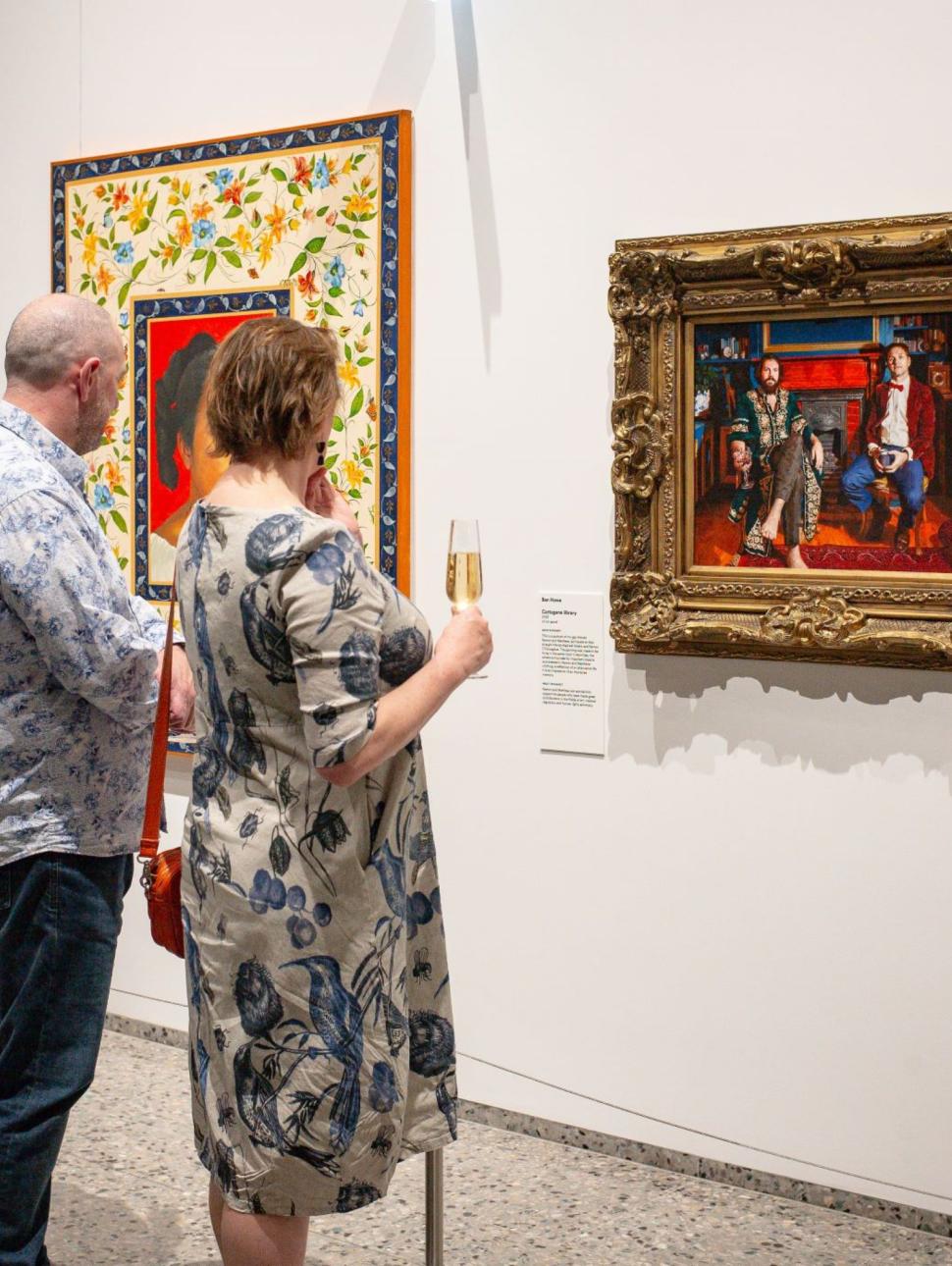 two patrons stand in front of a large colourful panting