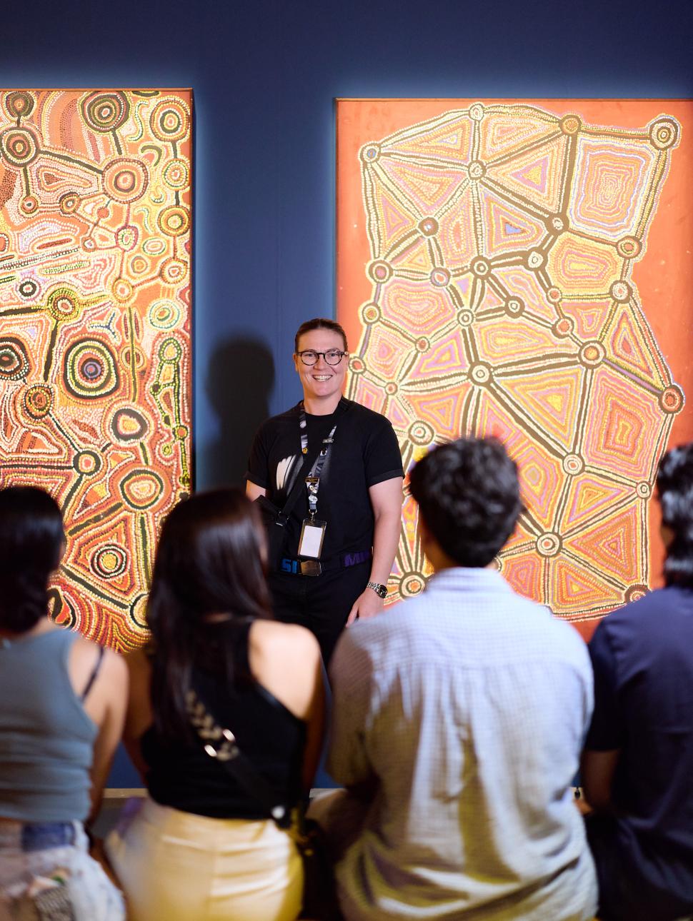 A museum staff members talking to visitor in an exhibition on a tour