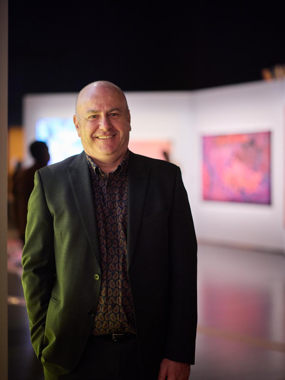 Head shot of curator Ross Chadwick from WA Museum smiling to camera in an exhibition.