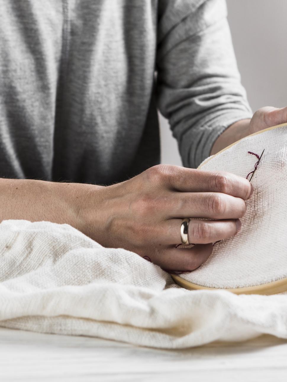 a close up of someone holding a fabric and stitching embroidery