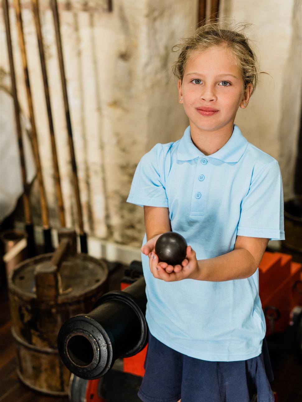 A young girl student holds an antique iron during a classroom session of the WA Shipwrecks Museum's education program Shipwrecked!