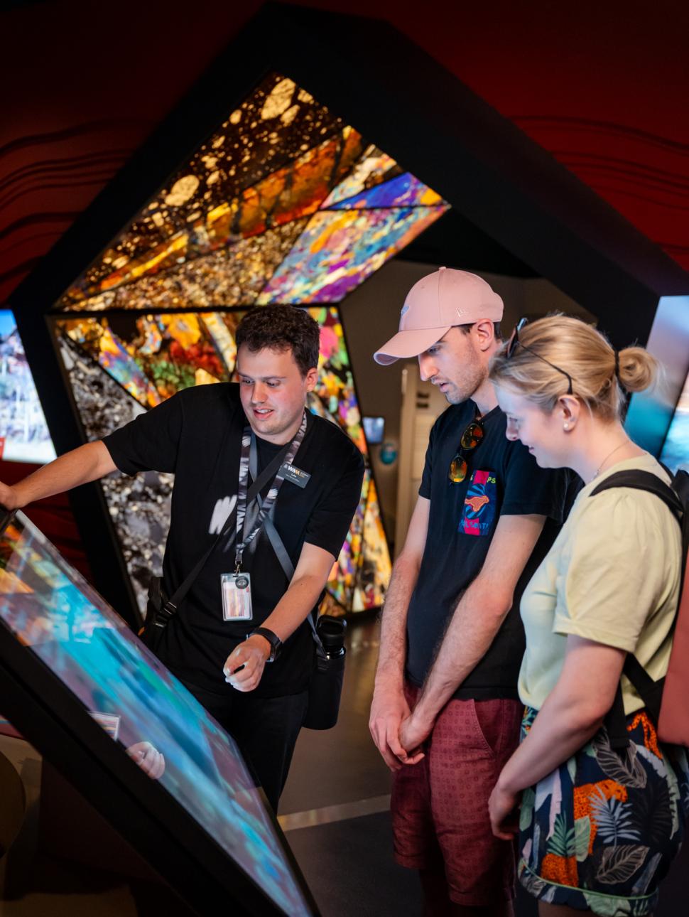 Two visitors on a tour with a staff member looking at a digital screen
