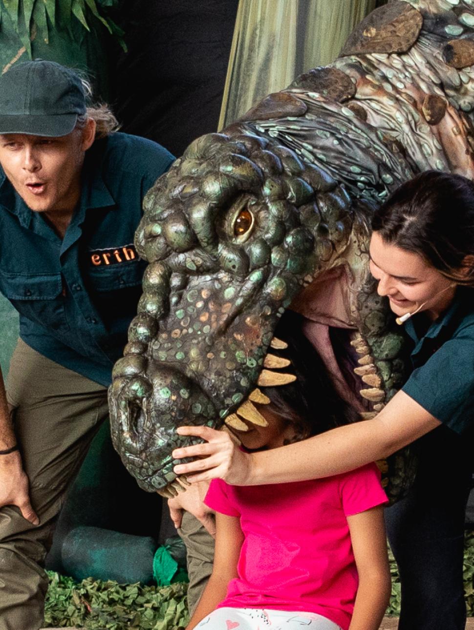 Giant dinosaur puppet towering over a little kid mid performance