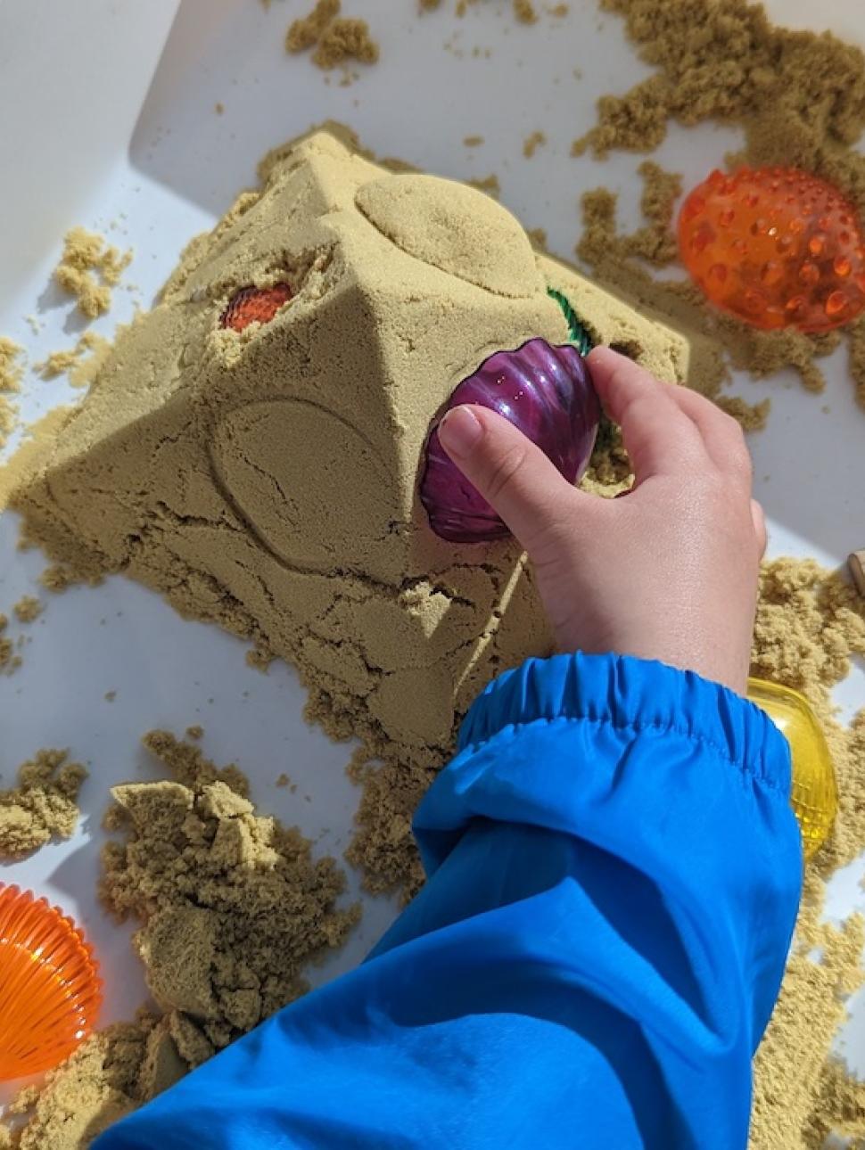 a overhead shot of a child creating a pyramid from sand 