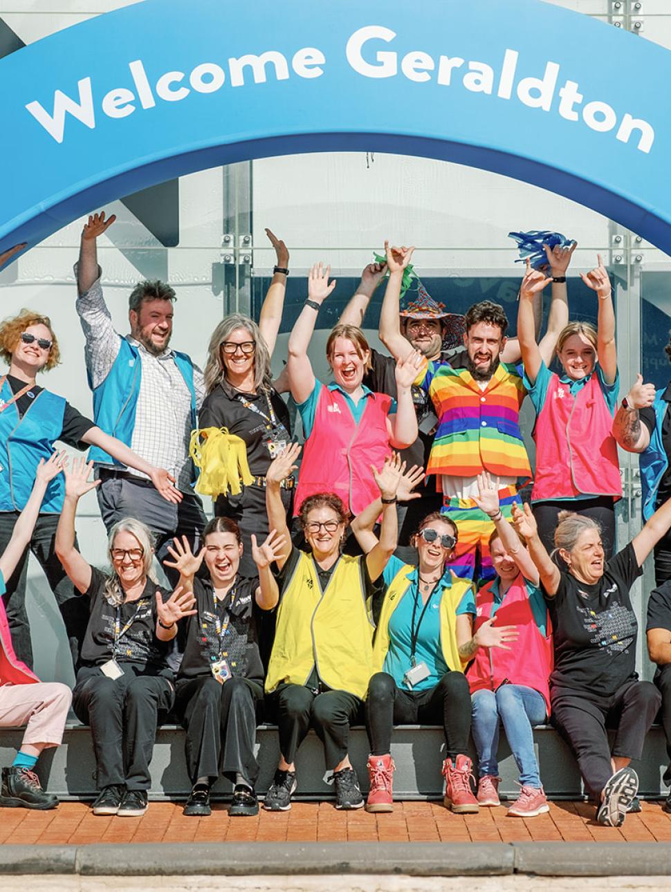 a group of happy people gather under an arch with words Welcome Geraldton