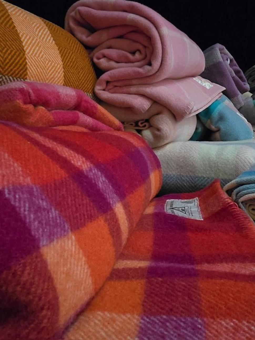 a pile of rolls of woollen fabrics of all colours 