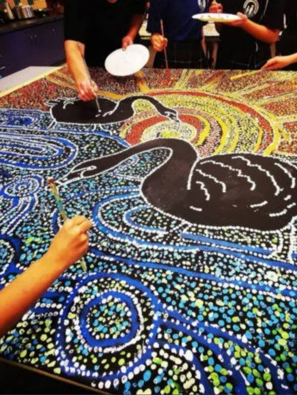 A group of young people are shown working on a community canvas art workshop hosted by Julianne Wade, local Whadjuk Nyoongar artist in Perth, Western Australia.