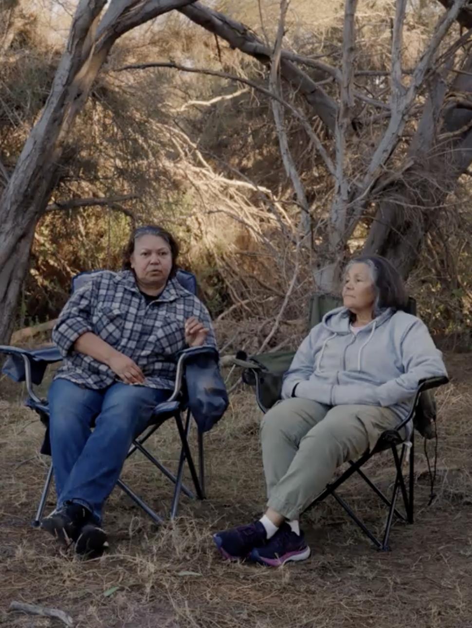two people sit in outdoor chairs in the outdoors contemplating  