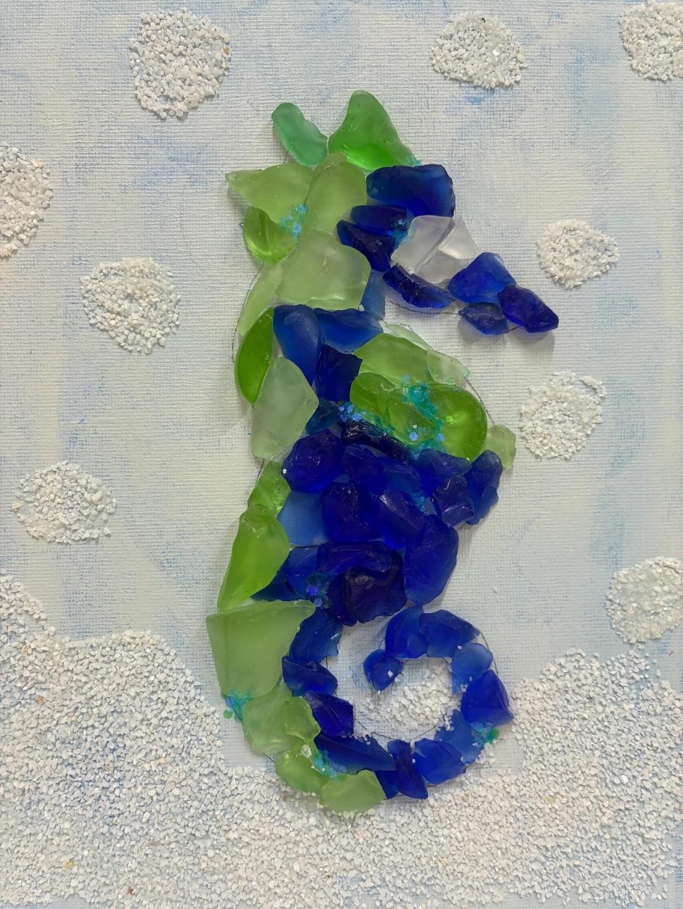 a colletion of sea glass arranged into a seahorse shape