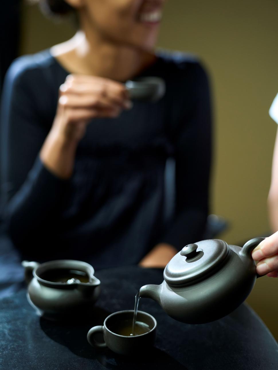 Person drinking chinese tea from tea pot