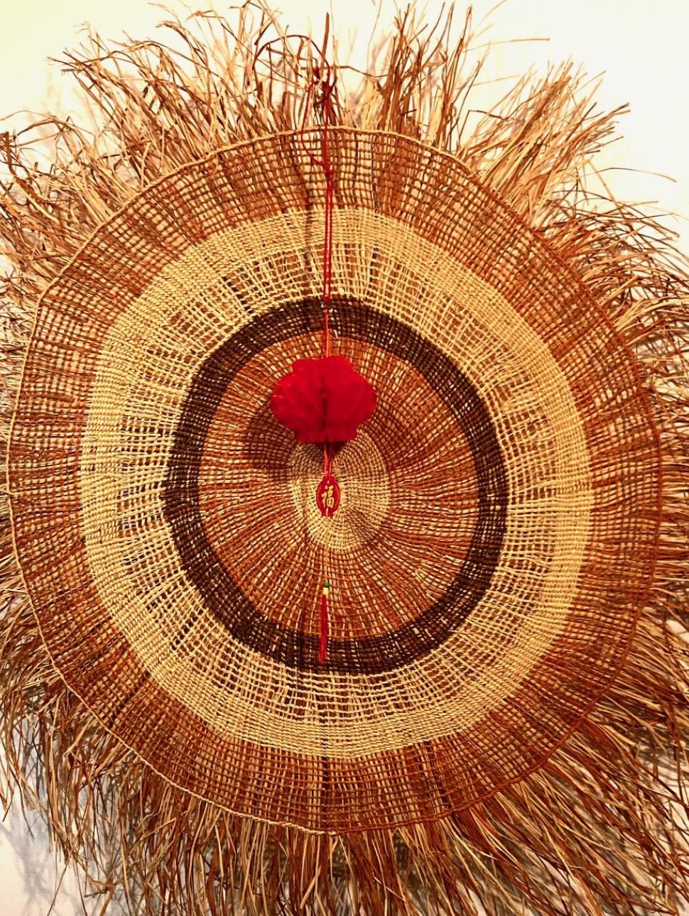 Woven artwork and Chinese lantern hanging side by side