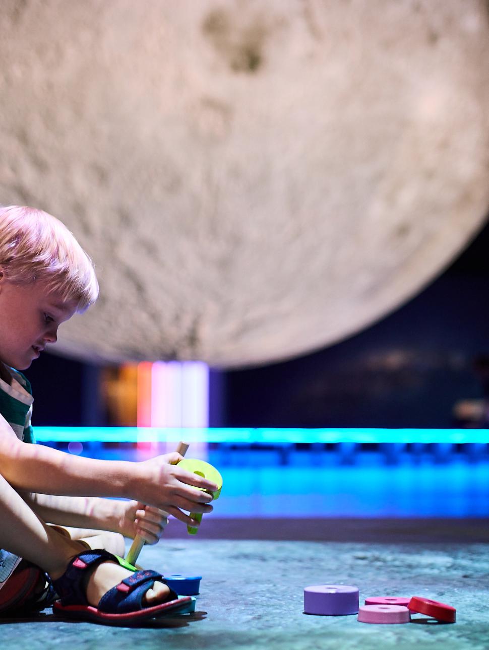 Toddler playing with blocks in front of large moon