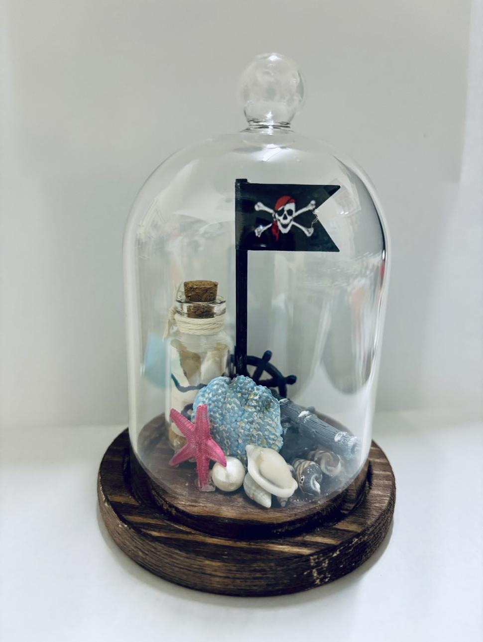 a small pirate treasure ocean scene within a mini glass cloche 
