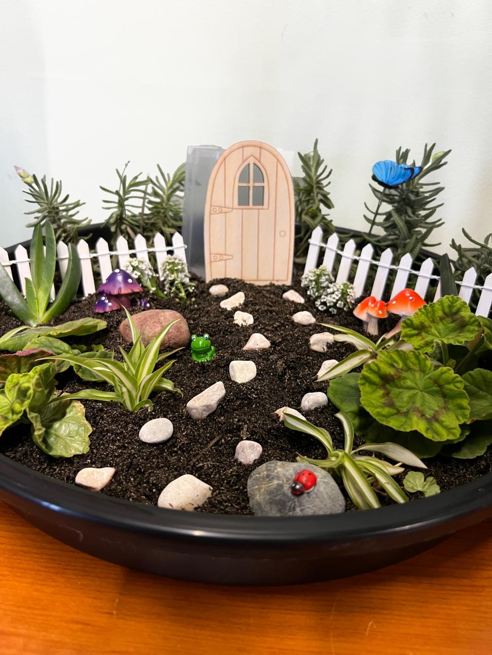 a bowl with miniature garden objects and plants