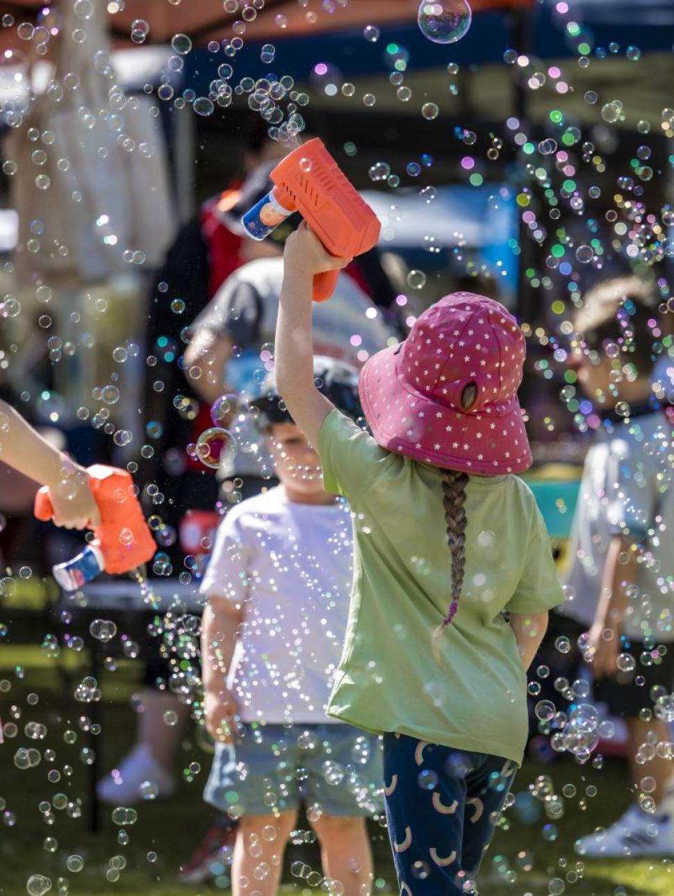 A group of children playing with Bubbles in a park