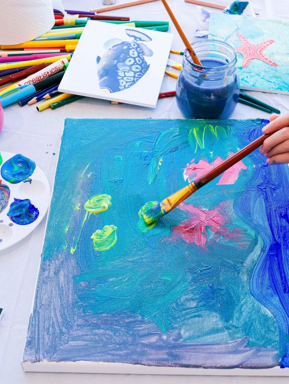 A Child painting a blue fish