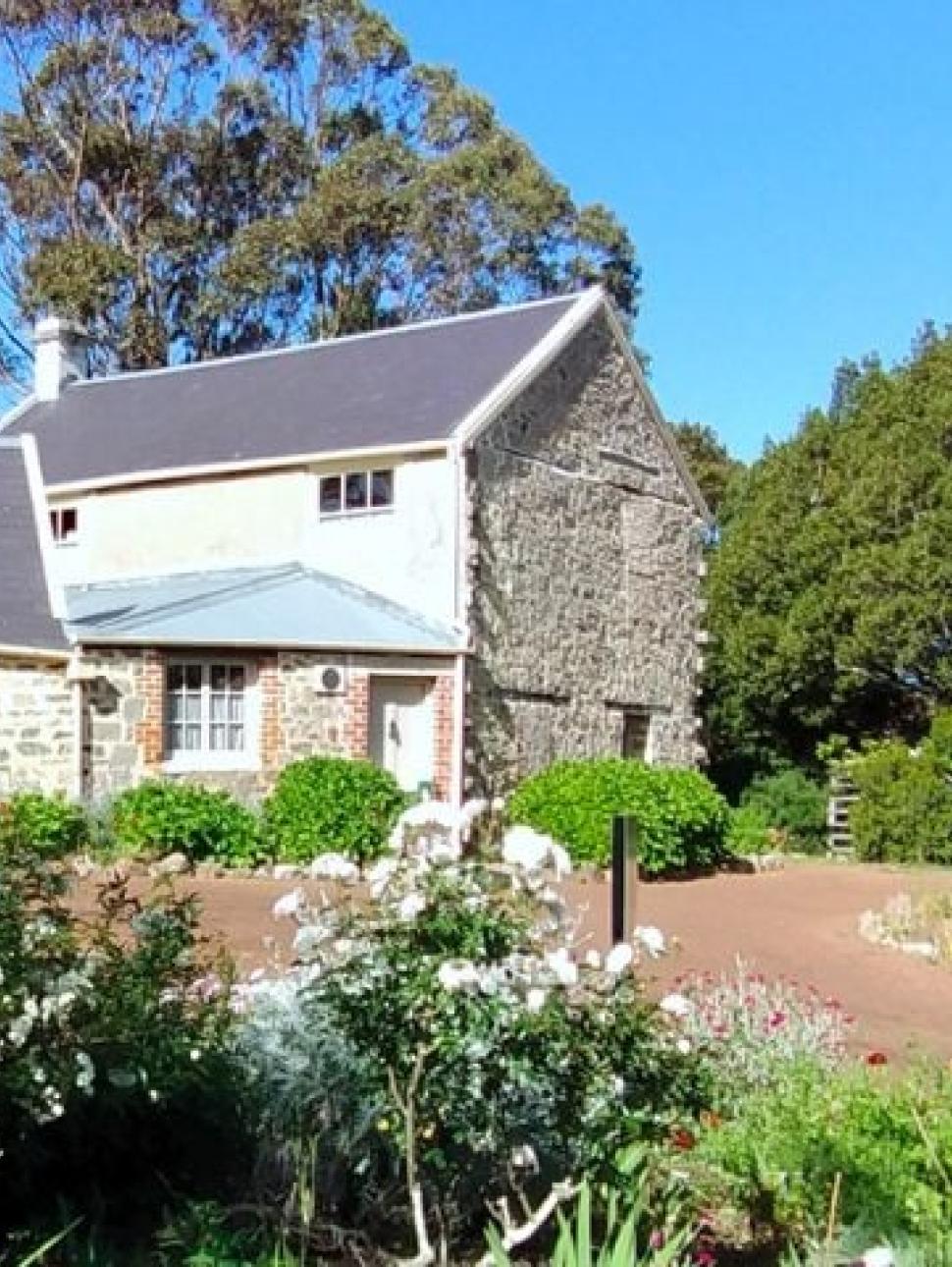 an outdoor image of a farm garden with a heritage building in the background