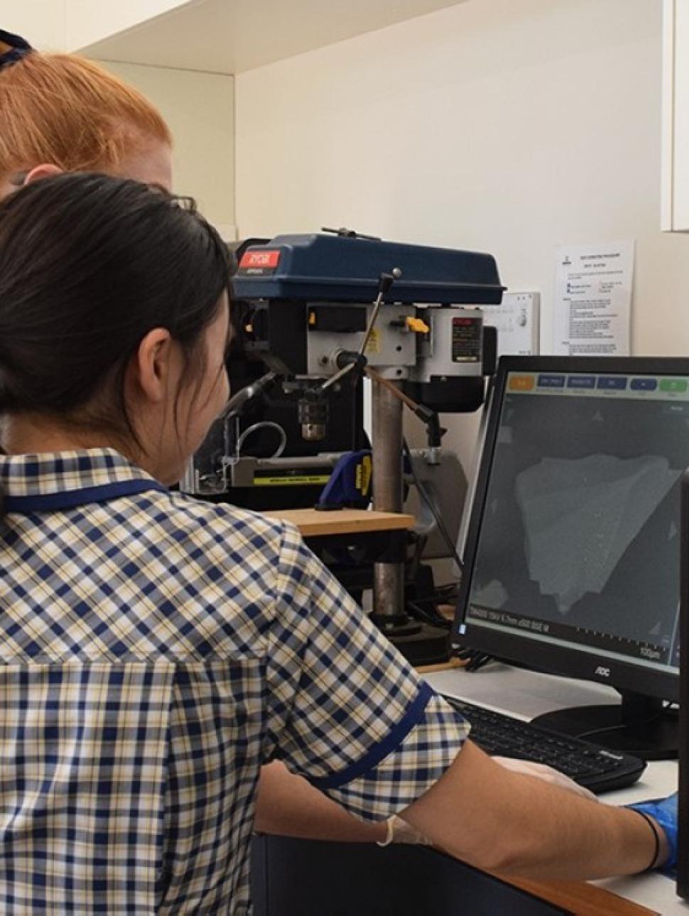 A group of school children looking at computer screen connect to a microscope