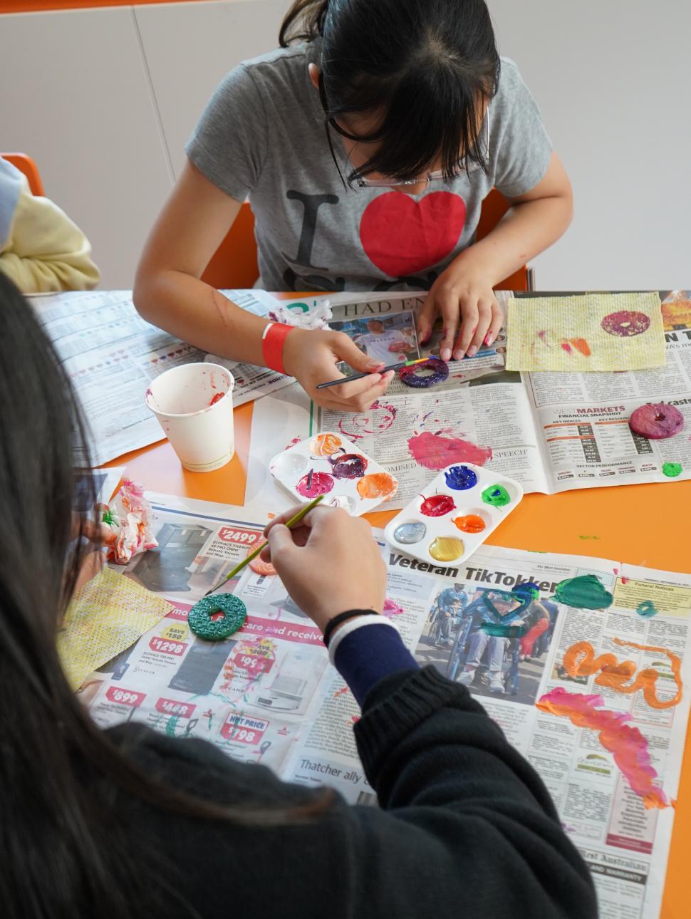 Two children painting jewellery items