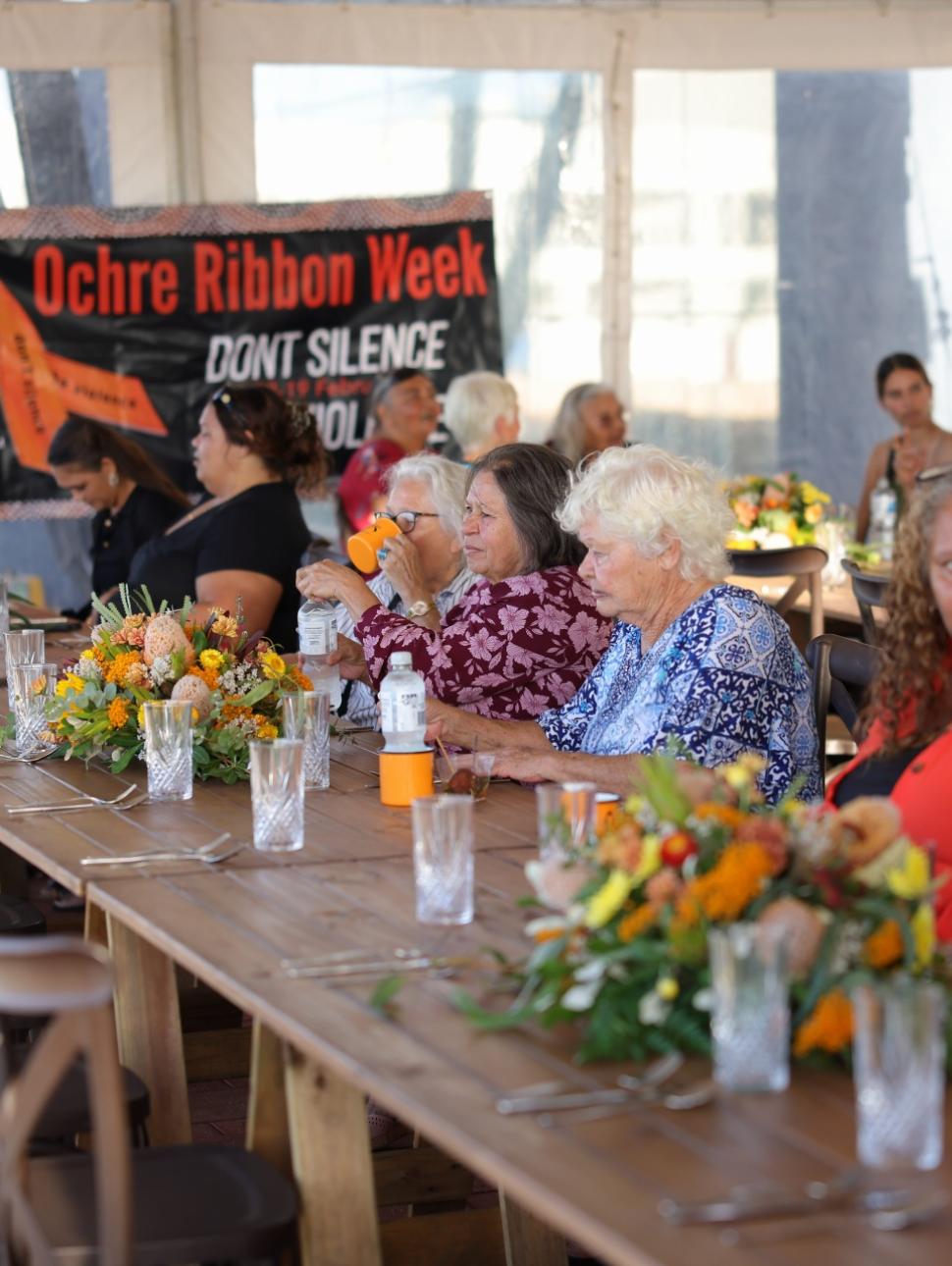 a long table decorated with floral settings and sitting at the table is many women