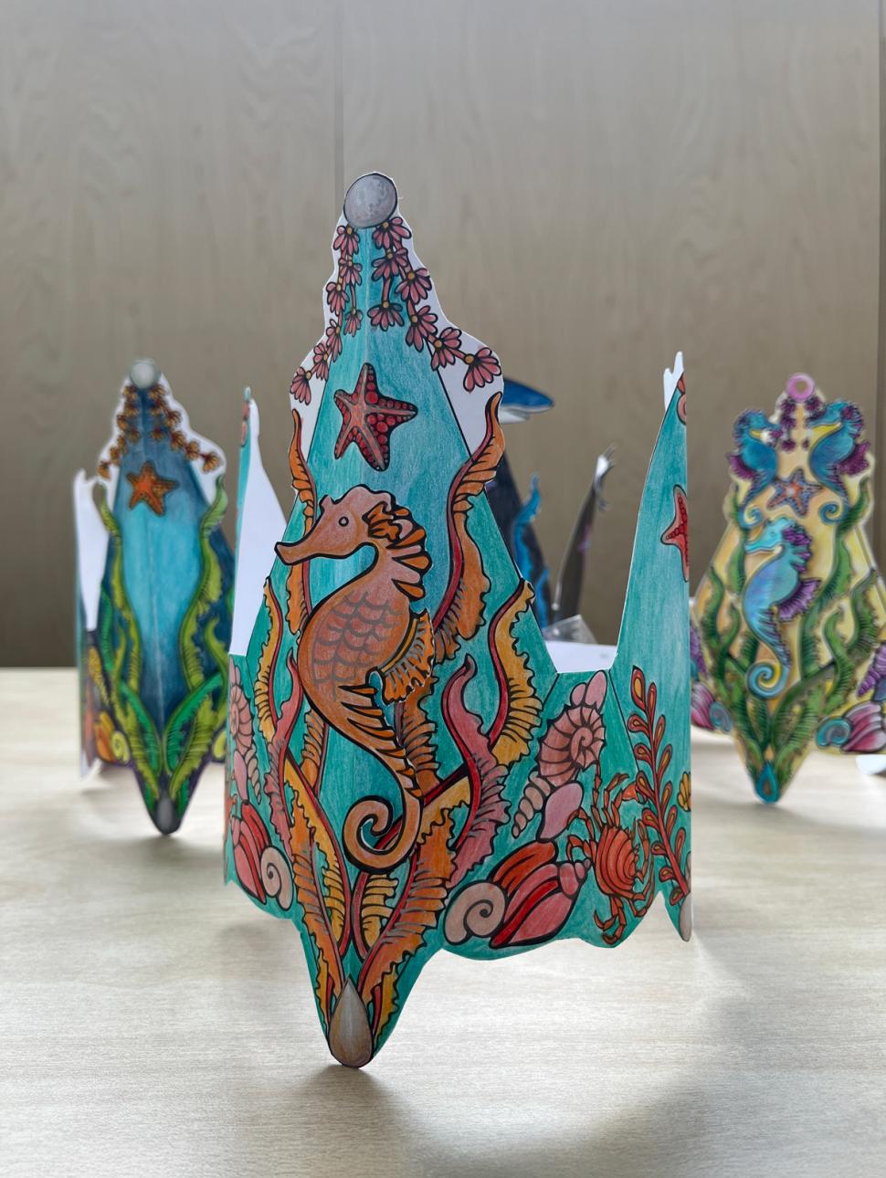 paper crowns with a sea scene decorated and coloured with pencils