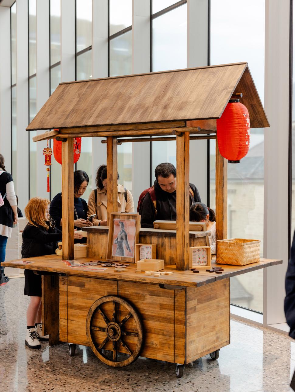 Group of people standing around a Chinese style cart looking down at activities