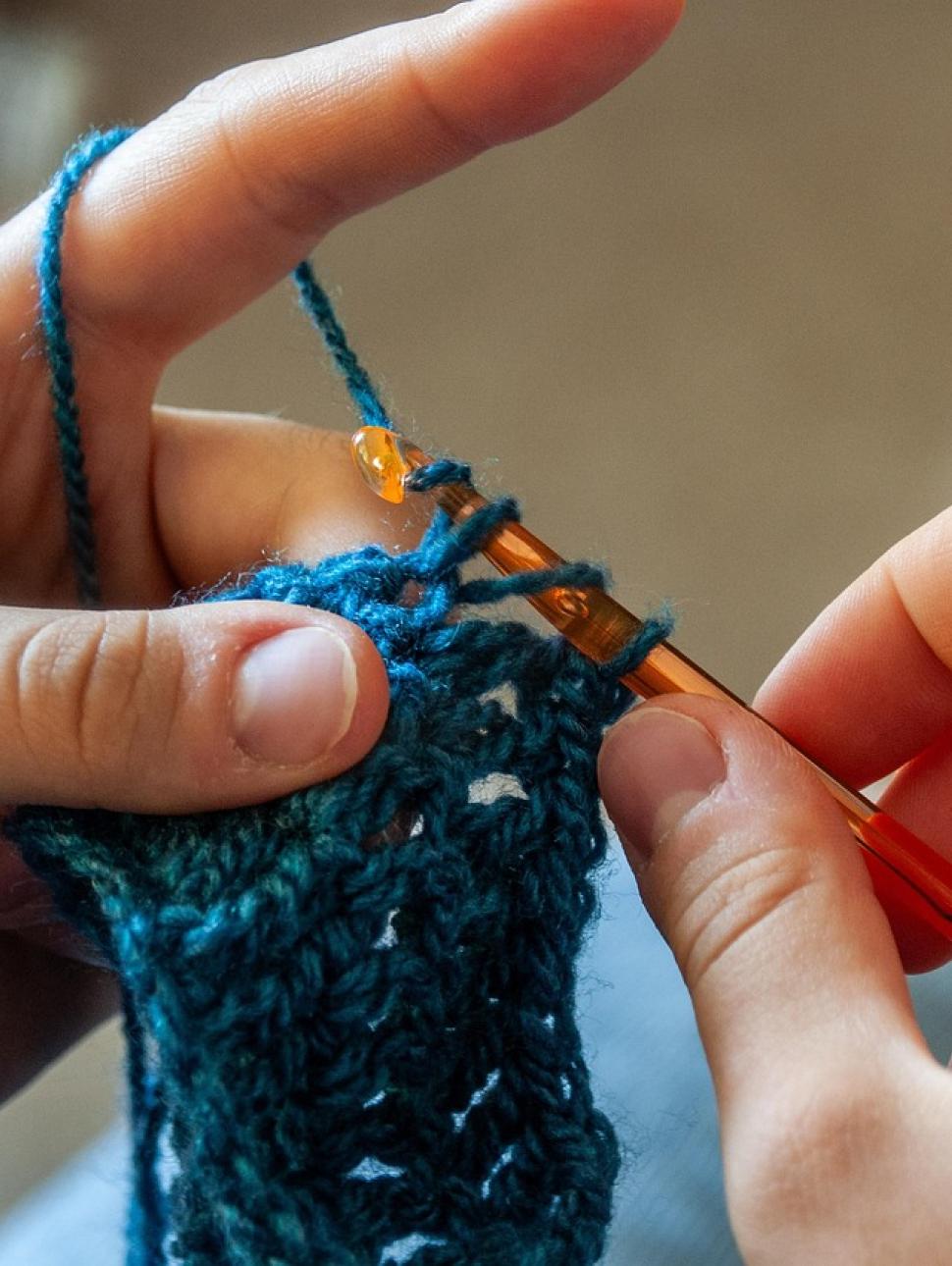 a close up of hands crocheting with yarn