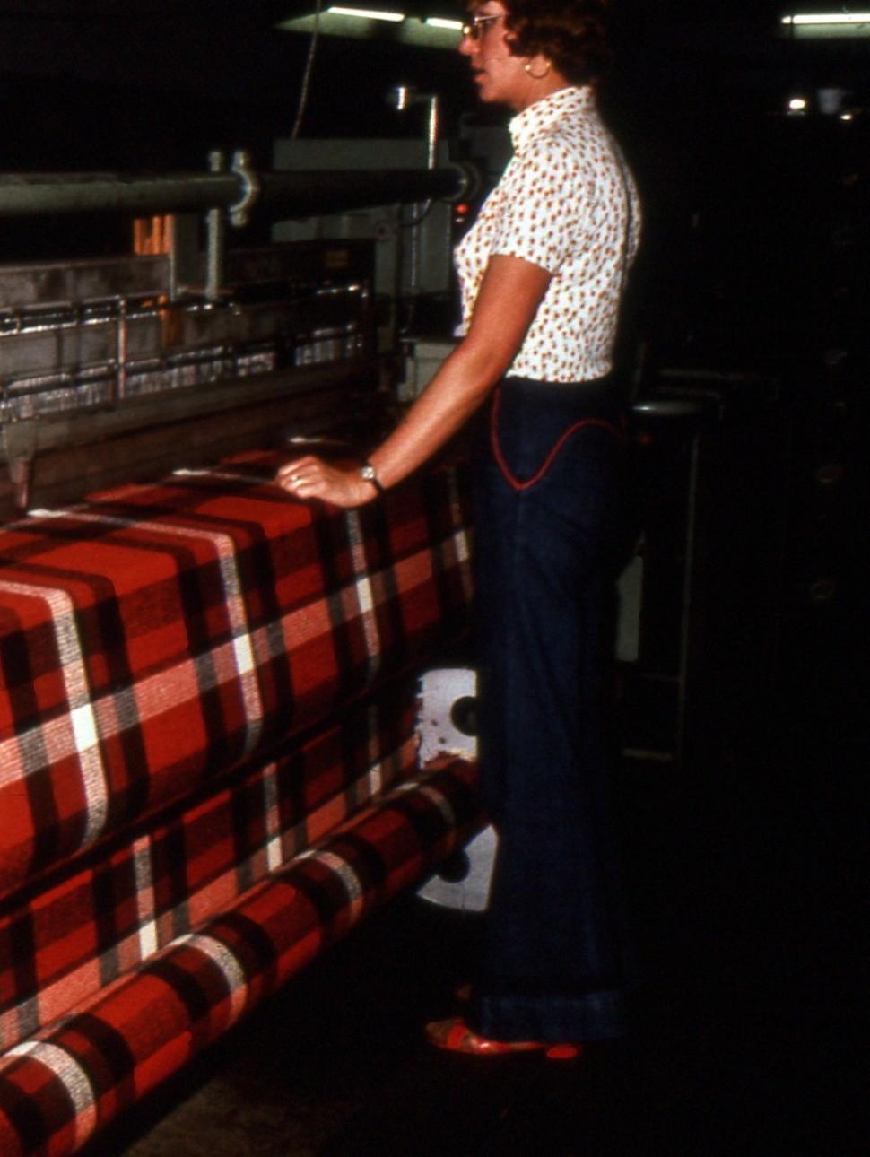 an archival photo of a person standing in front of a wool loom
