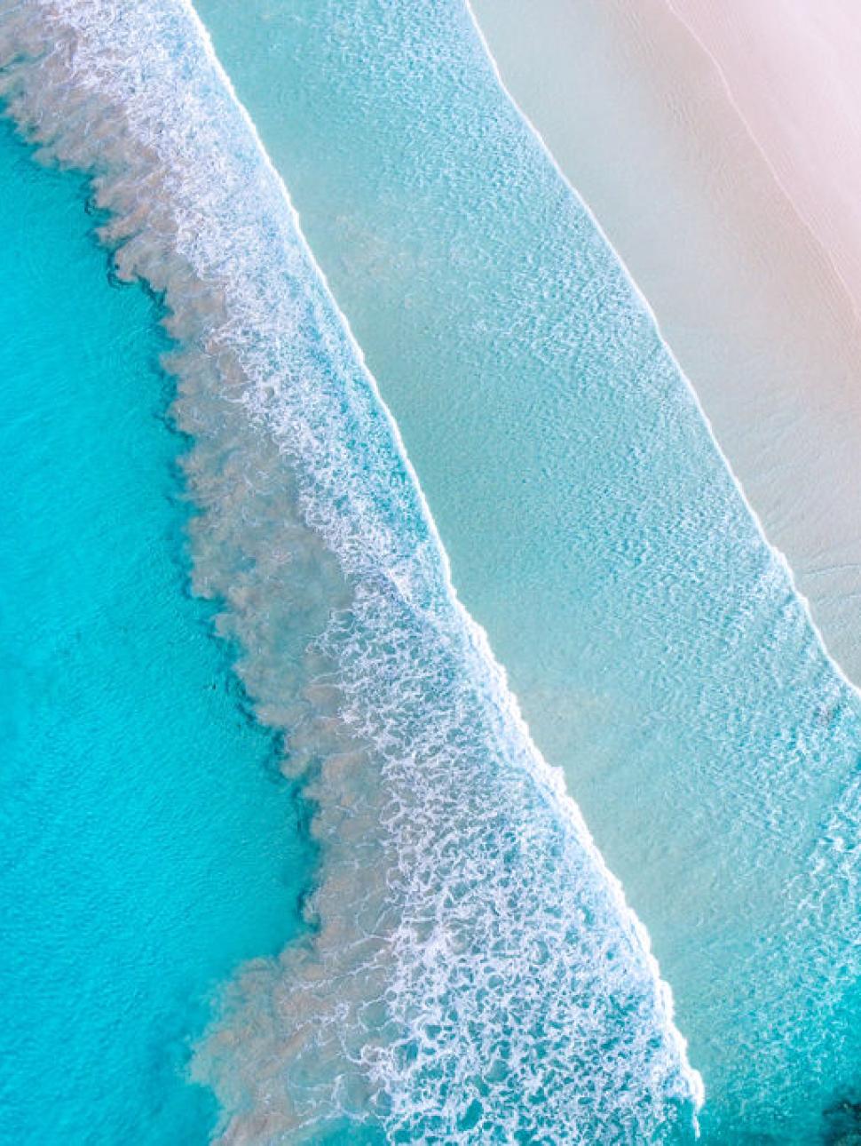 Aerial view of the blue ocean meeting the shoreline 