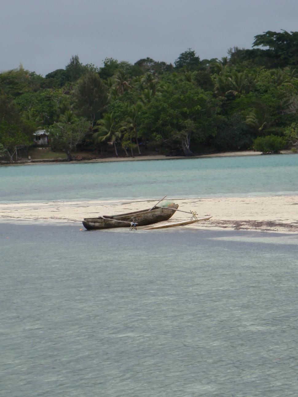 A traditional fishing boat with outrigger shown on a low-lying sandbar in Vanuatu.