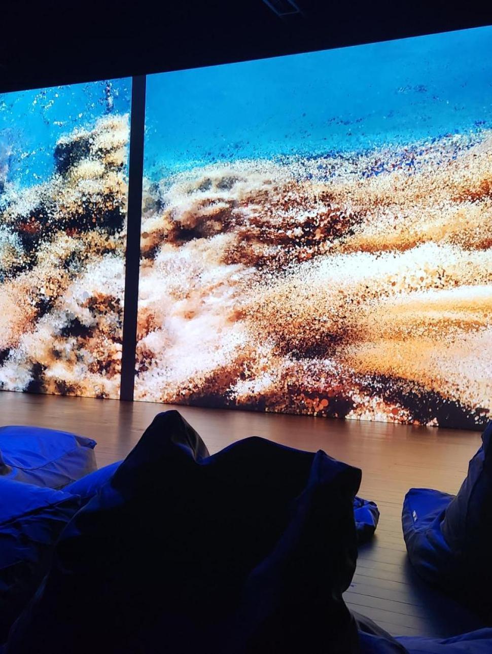 cinema theatre with beanbags in forefront and screen in the background with vibrant scenes.
