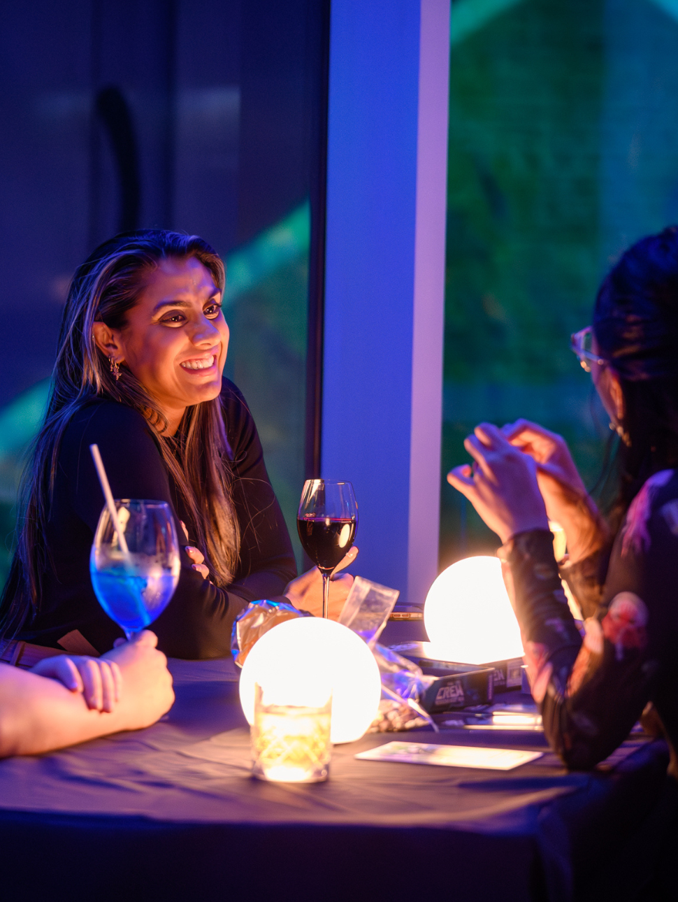 Two ladies having a conversation over a table with drinks.