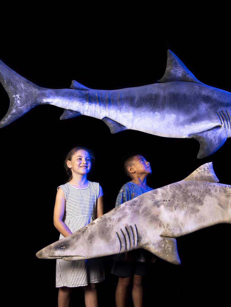 Two kids looking at shark puppets