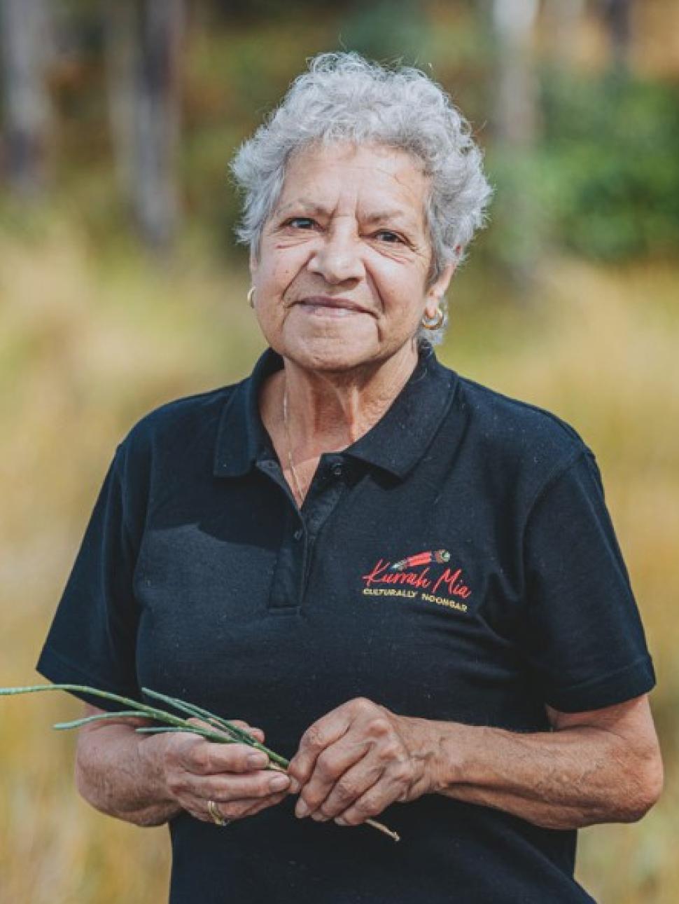 an adult person is outdoors amongst nature with a pleasant and approachable smile