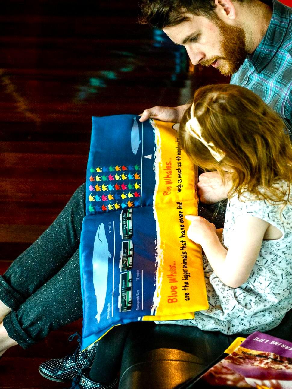 father reading to child in museum playspace about whales