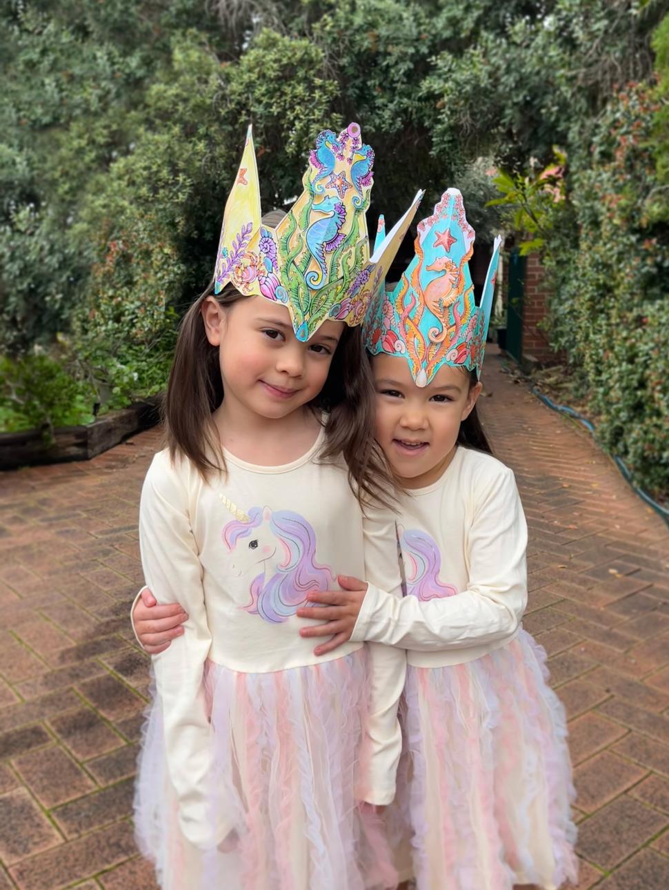 two children are wearing sea crown hats they crafted 