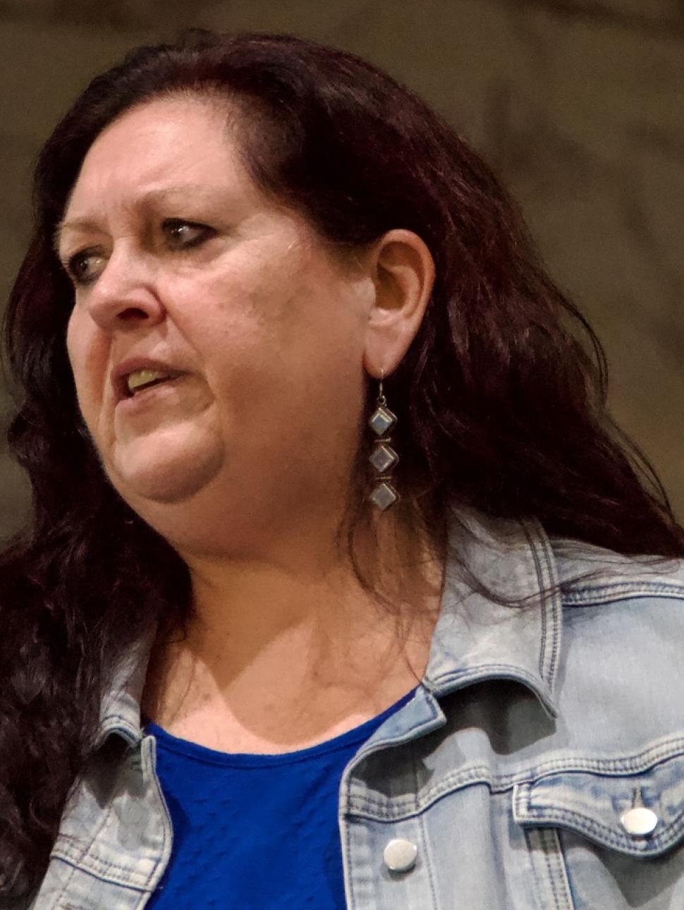 image of a person speaking. They are looking to the side as they are speaking and wear semi casual clothing