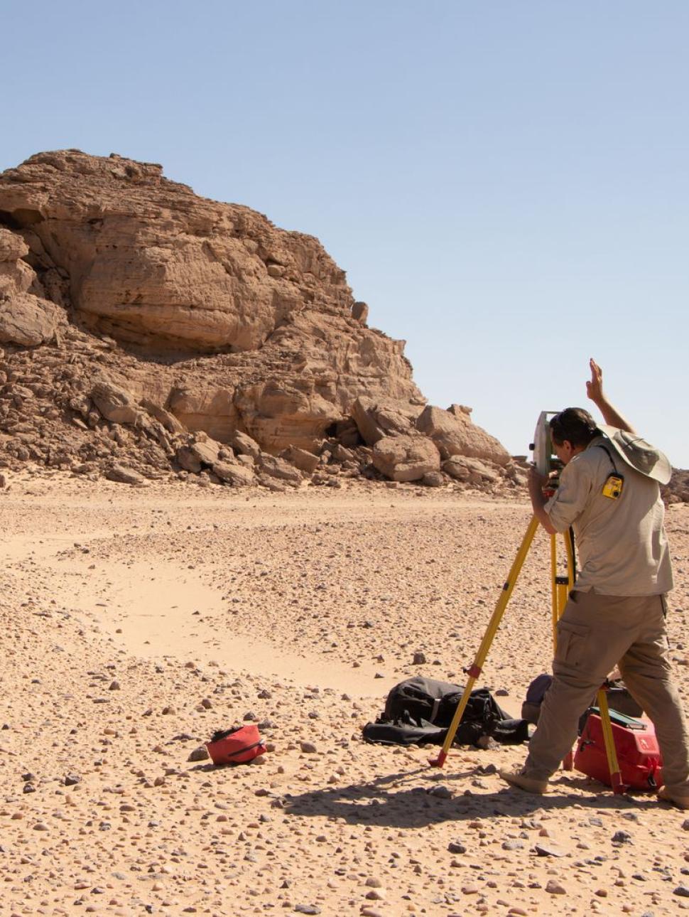 Landscape image of the Wadi el-Hudi Egyptian Desert. Researcher photographing rock formation.