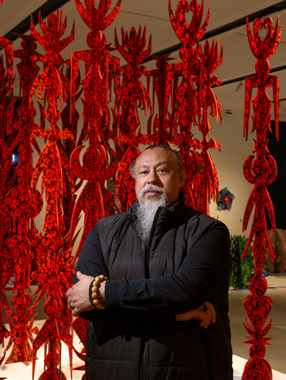 Man stands with his arms folded in front of artwork