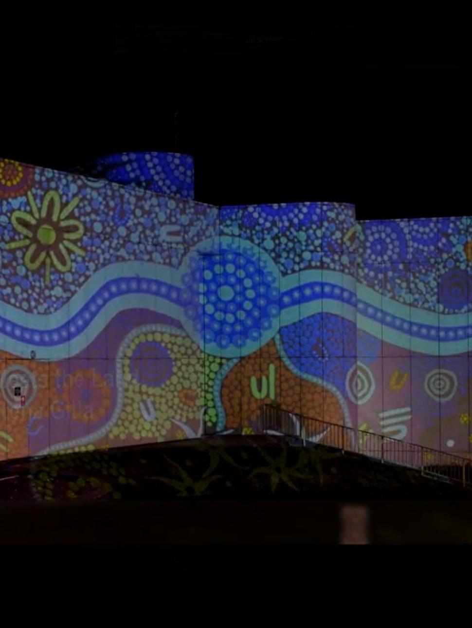 an exterior shot of a building with colourful light projections featuring artwork 